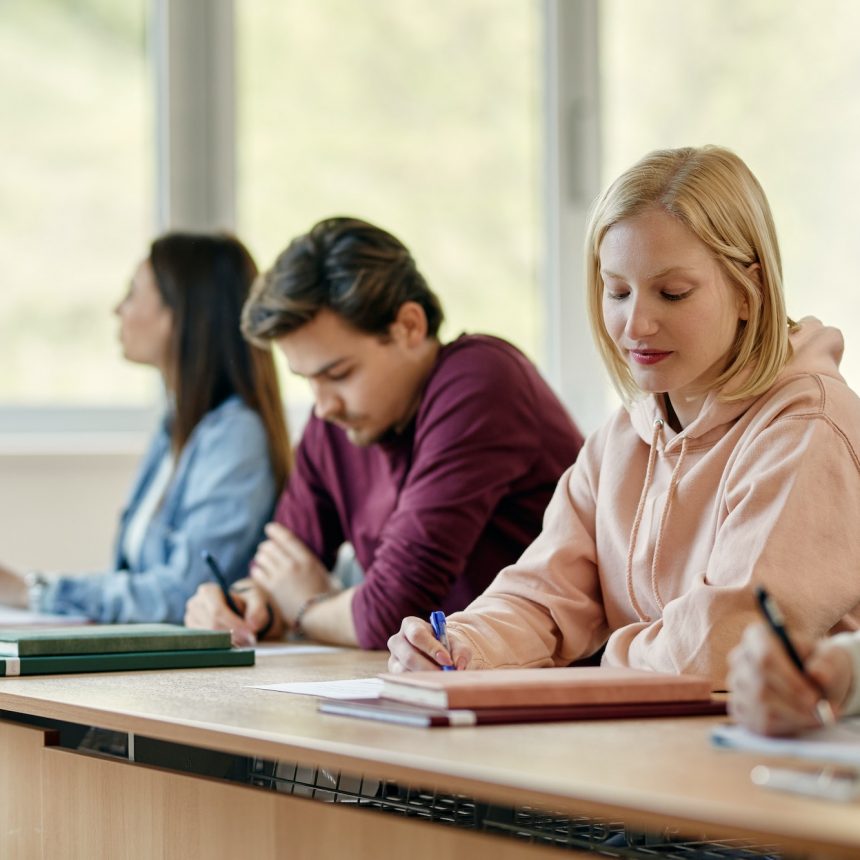 Female university student writing an exam in the classroom.